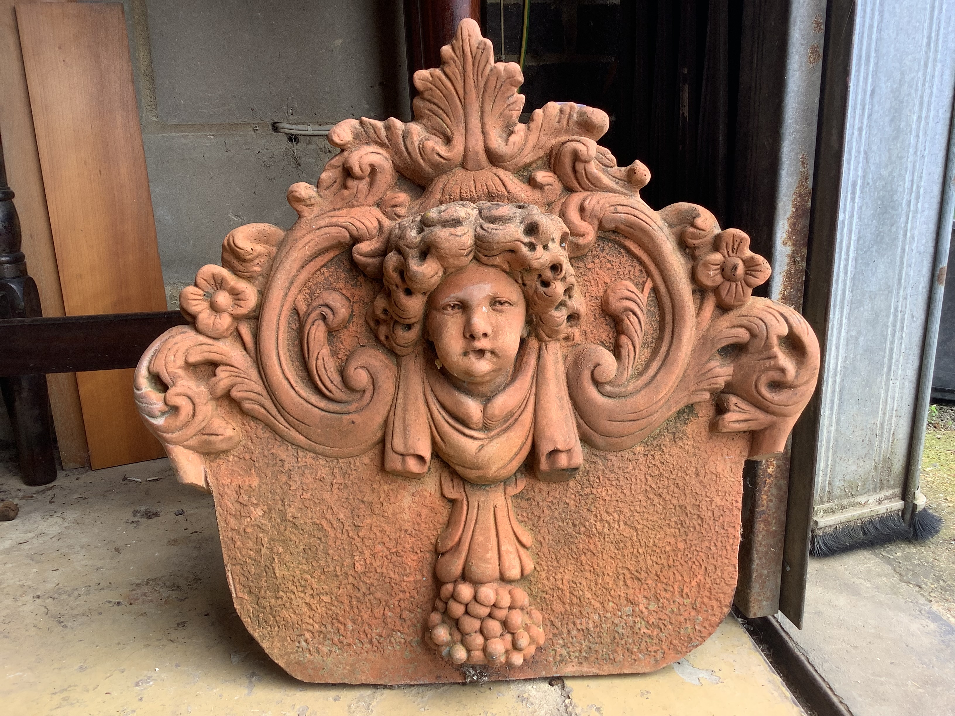 A terracotta cherub head garden wall plaque, width 54cm, height 54cm